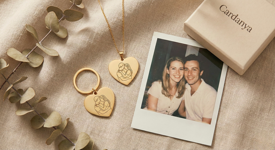 Cardanya gold heart-shaped necklace and keychain with custom line art engraving, placed next to a vintage polaroid photo representing an anniversary milestone.