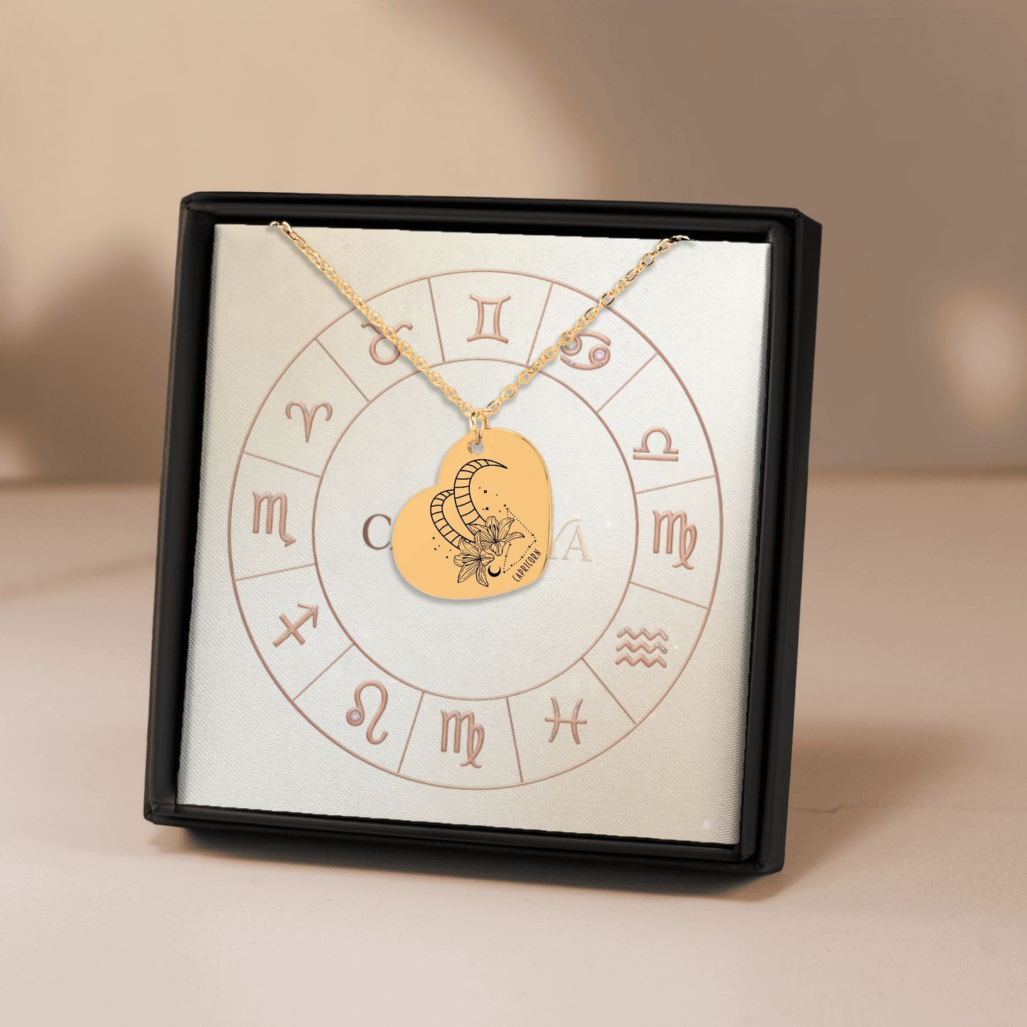Cardanya gold heart necklace featuring engraved Capricorn zodiac sign and floral design, displayed in an astrology-themed gift box.