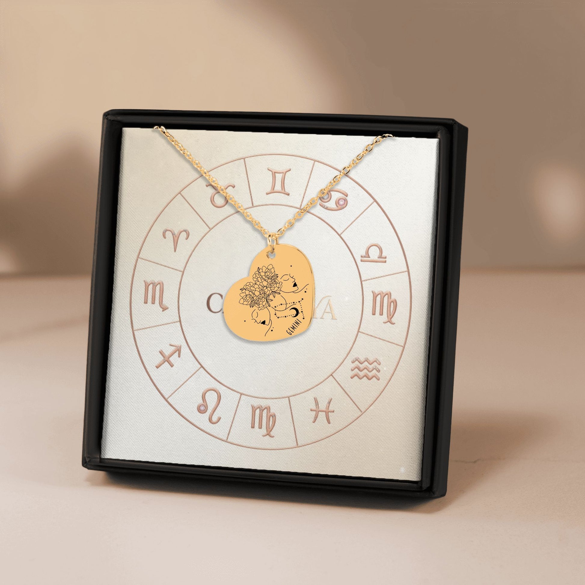 Cardanya gold heart necklace featuring engraved Gemini zodiac sign and floral design, displayed in an astrology-themed gift box.